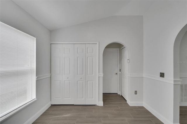 unfurnished bedroom featuring lofted ceiling and a closet