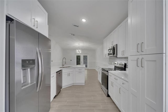 kitchen featuring sink, white cabinetry, decorative light fixtures, kitchen peninsula, and stainless steel appliances