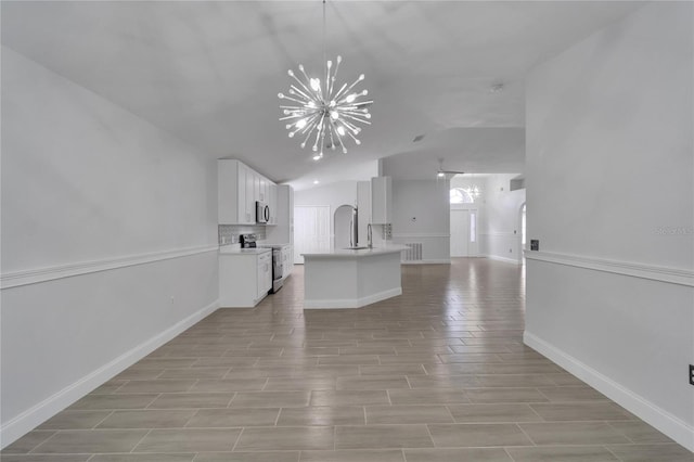 kitchen with lofted ceiling, decorative light fixtures, a chandelier, stainless steel appliances, and white cabinets