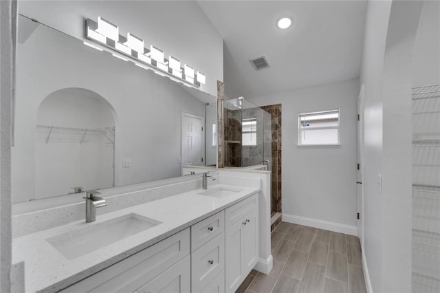 bathroom featuring walk in shower, vanity, and vaulted ceiling