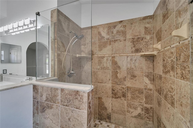 bathroom featuring vanity, vaulted ceiling, and tiled shower