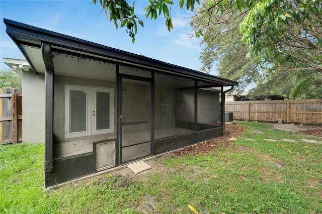 rear view of property featuring cooling unit, a yard, and a sunroom