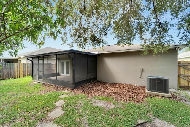 back of house with cooling unit, a sunroom, and a lawn