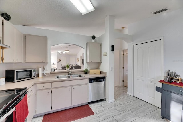 kitchen featuring appliances with stainless steel finishes, sink, light tile patterned floors, and a textured ceiling