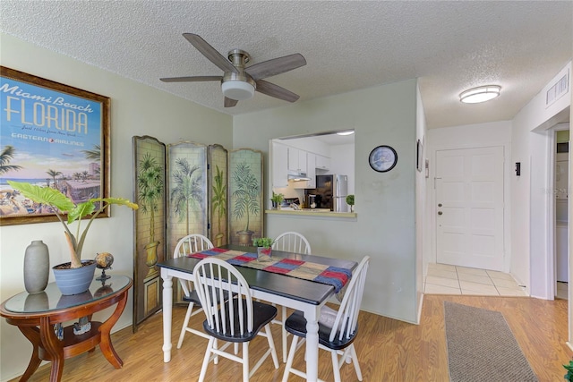 dining room with ceiling fan, light hardwood / wood-style floors, and a textured ceiling