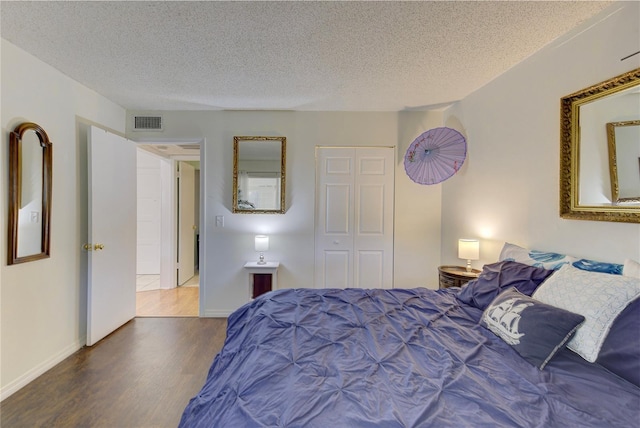 bedroom with wood-type flooring, a closet, and a textured ceiling