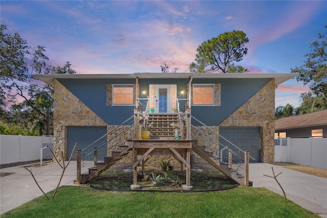 front of property featuring a garage, a porch, and a lawn