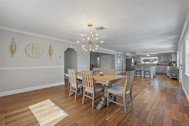 dining space featuring ornamental molding, dark wood-type flooring, and a chandelier