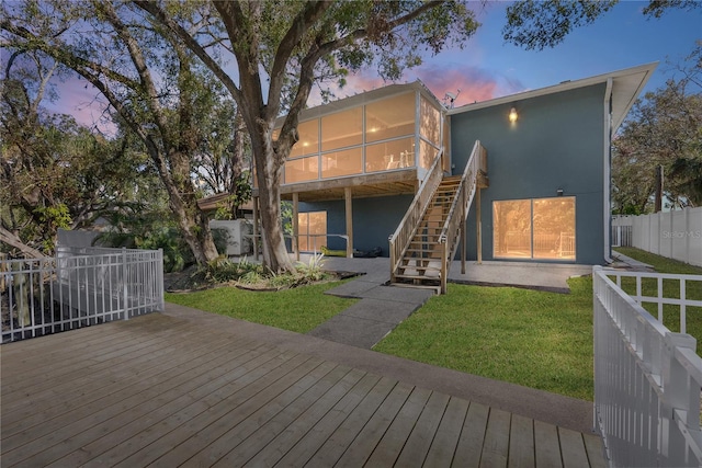 exterior space featuring a sunroom, a yard, and a deck