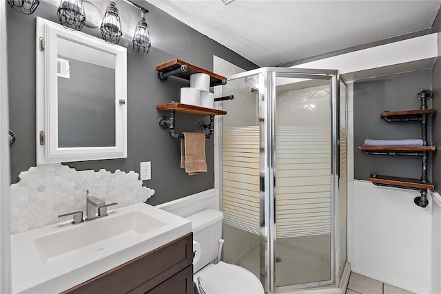 bathroom featuring tile patterned floors, vanity, toilet, and a shower with shower door