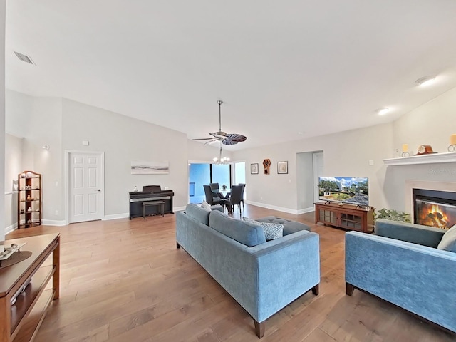 living room with lofted ceiling, a chandelier, and light wood-type flooring