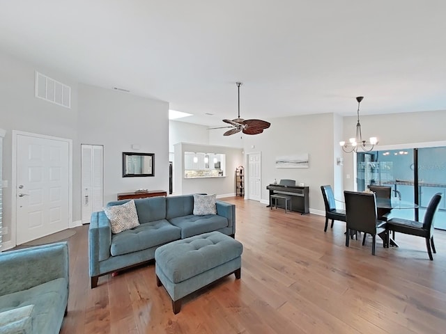 living room featuring ceiling fan with notable chandelier and light hardwood / wood-style flooring