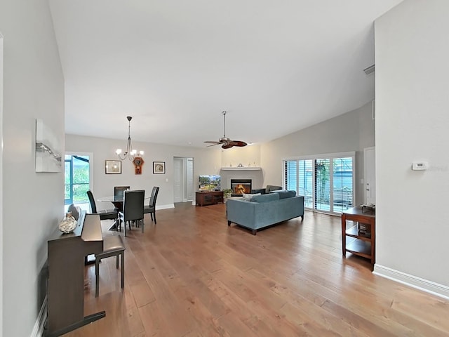 living room featuring plenty of natural light, ceiling fan with notable chandelier, and light hardwood / wood-style floors