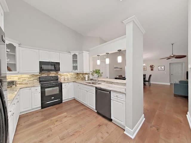 kitchen with sink, white cabinetry, light stone counters, tasteful backsplash, and black appliances