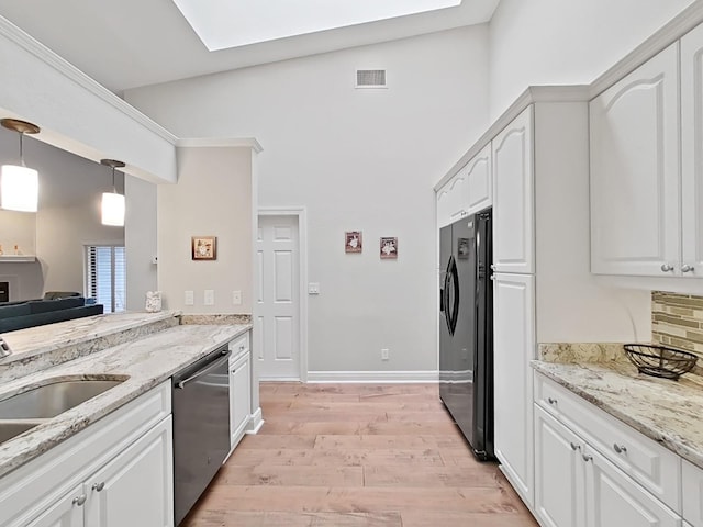 kitchen featuring white cabinetry, a skylight, stainless steel appliances, light stone countertops, and decorative light fixtures