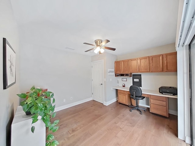 home office with ceiling fan, built in desk, and light wood-type flooring