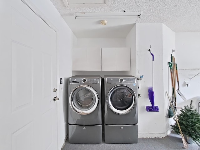 washroom with cabinets, a textured ceiling, and independent washer and dryer