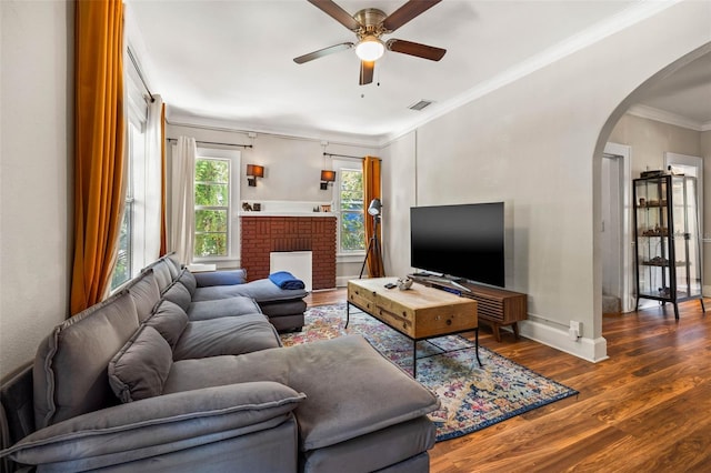 living room featuring a fireplace, ornamental molding, dark hardwood / wood-style floors, and ceiling fan