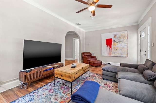 living room featuring wood-type flooring, ornamental molding, and ceiling fan