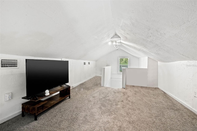 additional living space with carpet floors, vaulted ceiling, and a textured ceiling