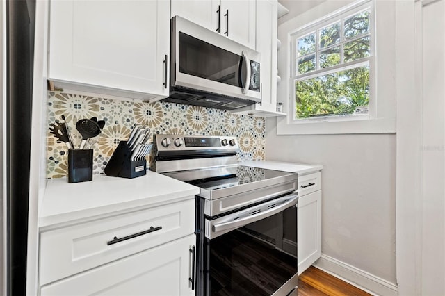 kitchen with tasteful backsplash, white cabinetry, appliances with stainless steel finishes, and wood-type flooring