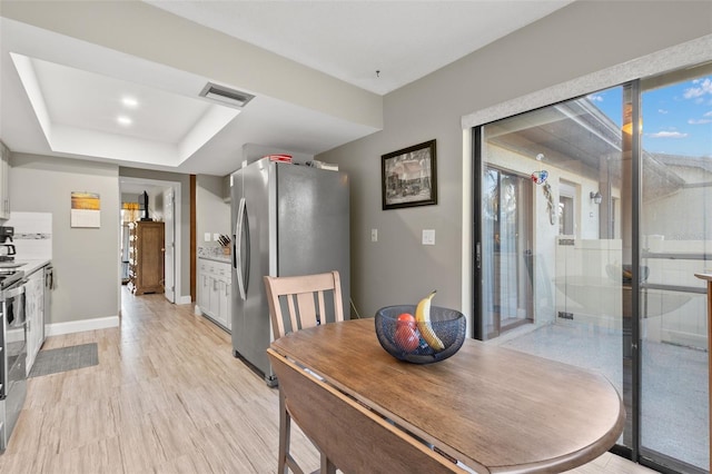 dining area featuring a tray ceiling and light hardwood / wood-style floors