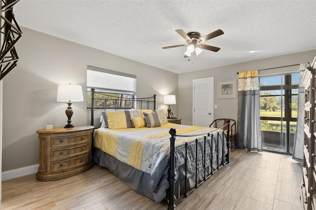 bedroom with multiple windows, light wood-type flooring, access to outside, and a textured ceiling