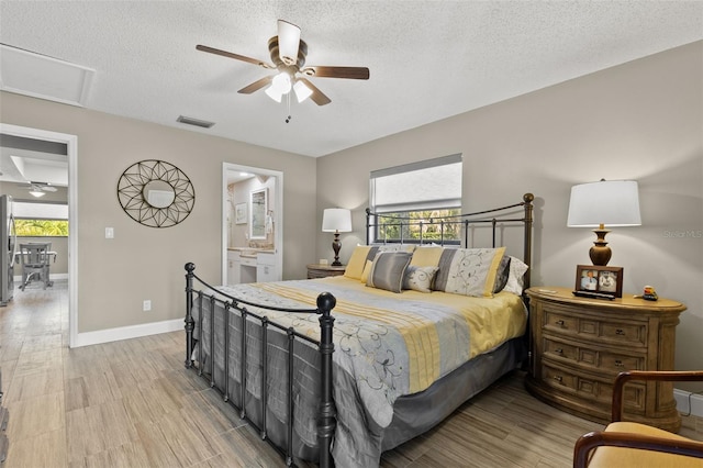 bedroom featuring ceiling fan, ensuite bath, light hardwood / wood-style floors, and a textured ceiling