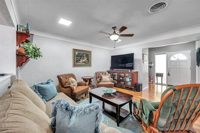 living room with ceiling fan, light hardwood / wood-style floors, and a textured ceiling