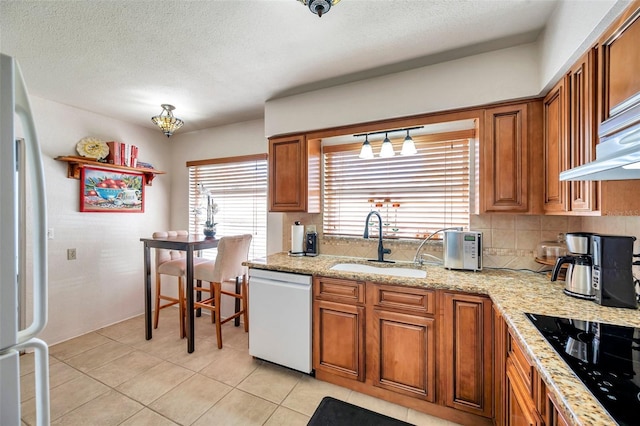 kitchen featuring dishwasher, sink, fridge, black electric stovetop, and light tile patterned floors