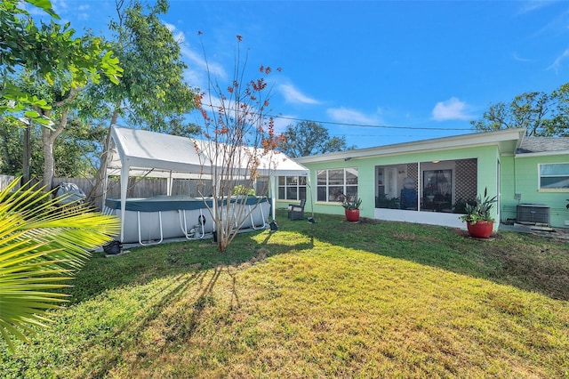 view of yard with a fenced in pool, a sunroom, and central AC unit