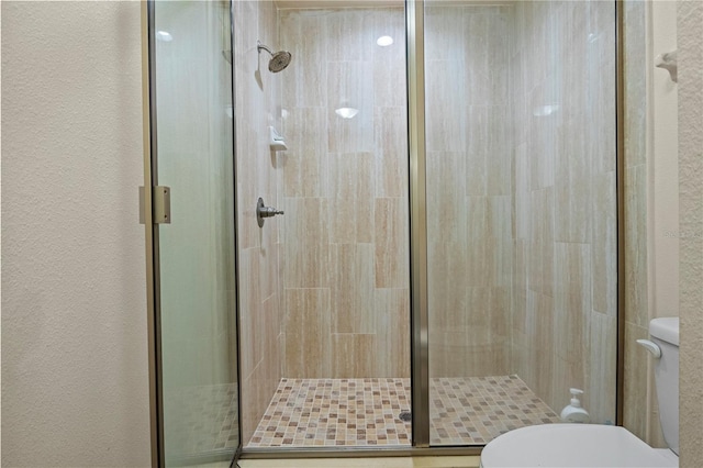 bathroom with a shower with door and toilet