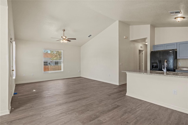 unfurnished living room with lofted ceiling, a textured ceiling, dark hardwood / wood-style floors, and ceiling fan