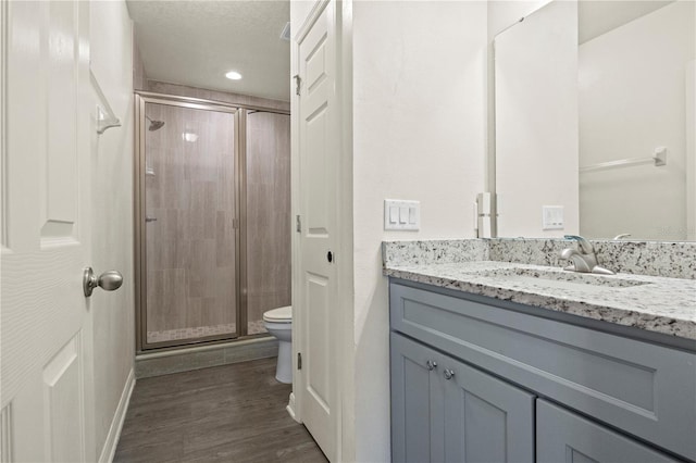 bathroom with vanity, wood-type flooring, a shower with door, and toilet