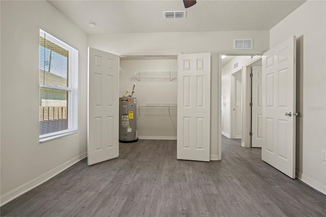 unfurnished bedroom with hardwood / wood-style flooring, electric water heater, ceiling fan, and a closet