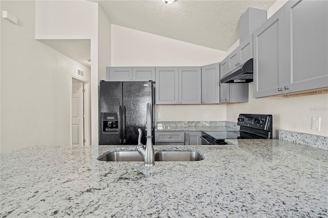 kitchen featuring lofted ceiling, sink, gray cabinetry, light stone counters, and black appliances