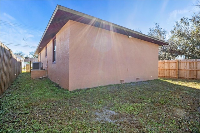 view of side of home featuring cooling unit and a lawn