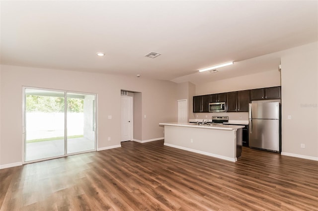 kitchen with dark brown cabinets, a center island with sink, dark hardwood / wood-style floors, and appliances with stainless steel finishes