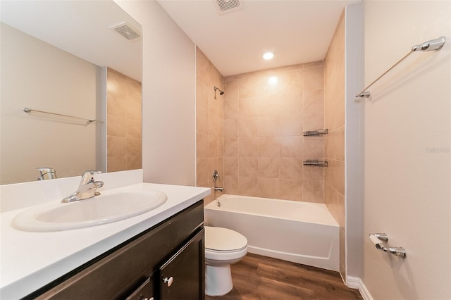 full bathroom with vanity, hardwood / wood-style flooring, tiled shower / bath combo, and toilet