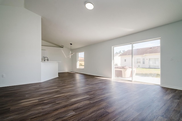 unfurnished living room with a healthy amount of sunlight, lofted ceiling, dark hardwood / wood-style floors, and sink