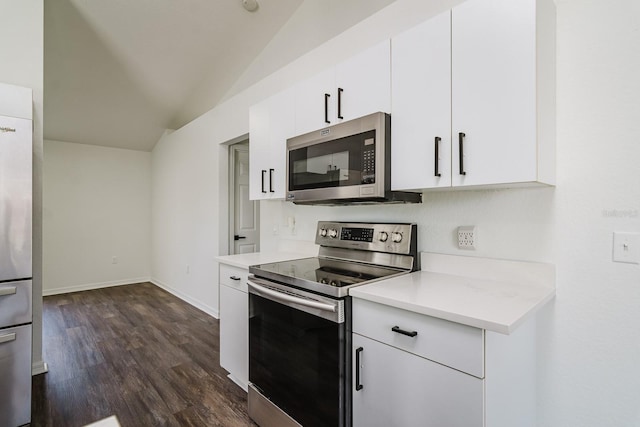 kitchen featuring dark wood-type flooring, vaulted ceiling, white cabinets, and appliances with stainless steel finishes