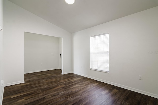 empty room with dark wood-type flooring and vaulted ceiling