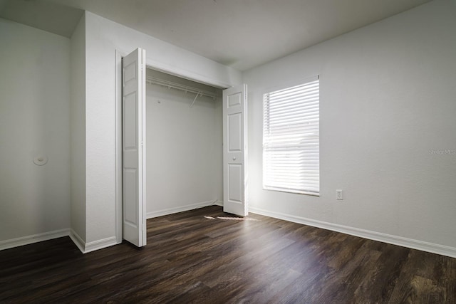 unfurnished bedroom with dark hardwood / wood-style floors and a closet