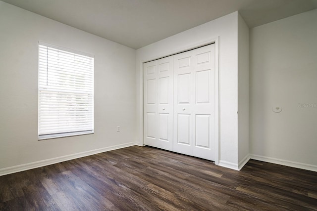 unfurnished bedroom featuring dark wood-type flooring and a closet