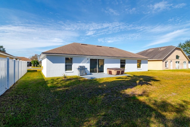 back of house featuring a patio area, a hot tub, and a lawn