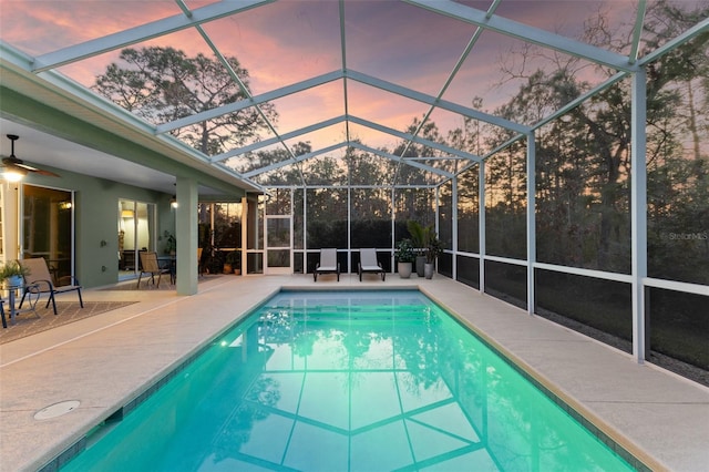 pool at dusk featuring a patio and glass enclosure