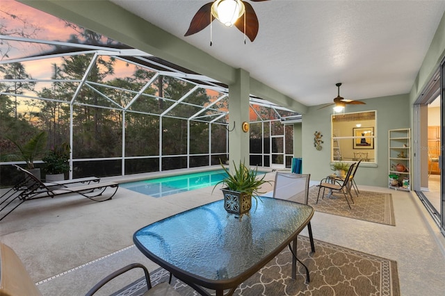 pool at dusk featuring a patio, a lanai, and ceiling fan