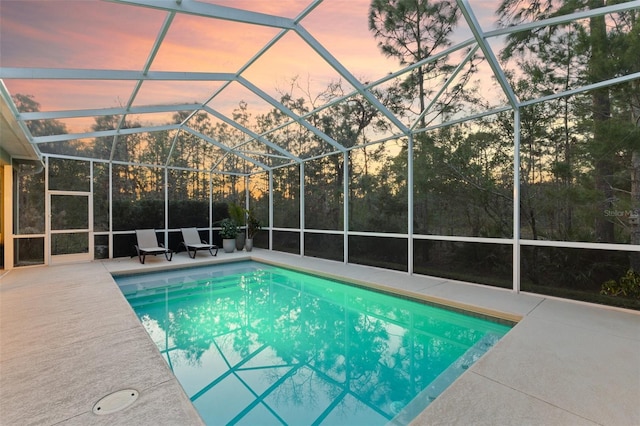 pool at dusk with a lanai and a patio area