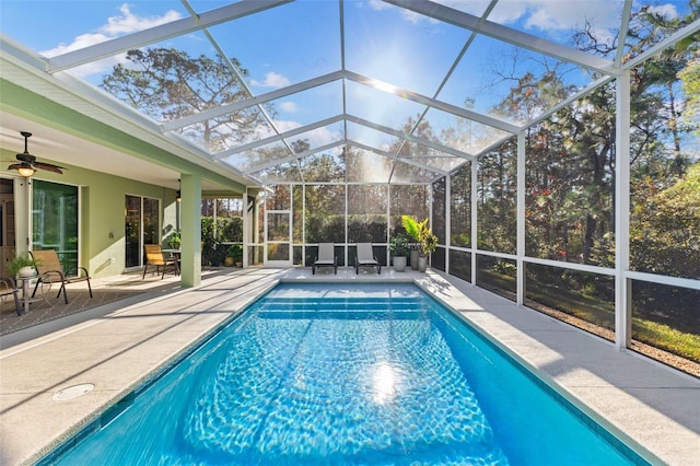 view of swimming pool with a patio, ceiling fan, and glass enclosure