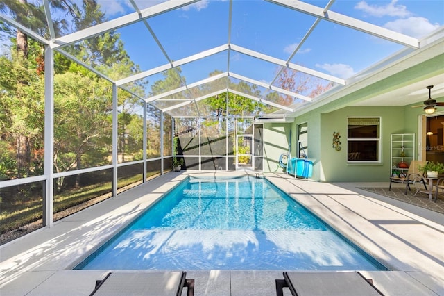 view of swimming pool featuring a patio area, ceiling fan, and glass enclosure